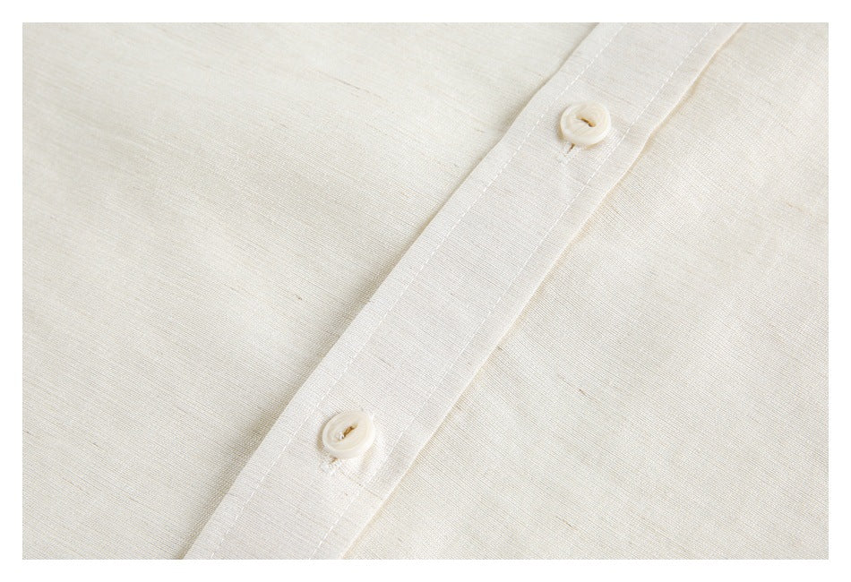 Close-up of an ivory shirt's button placket with two buttons and visible stitching.