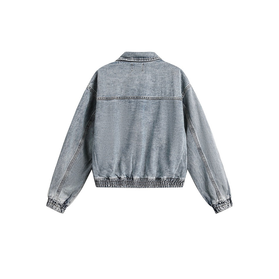 Back view of a light blue denim jacket with a pointed collar, dropped shoulders, and gathered cuffs and hem, shown flat.
