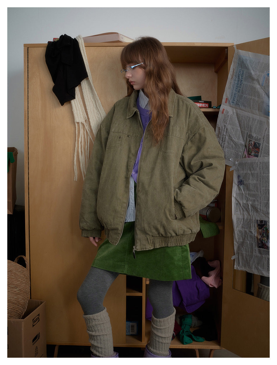A model stands in an oversized olive zip-front jacket with a wide collar, chest pockets and gathered hem and cuffs.