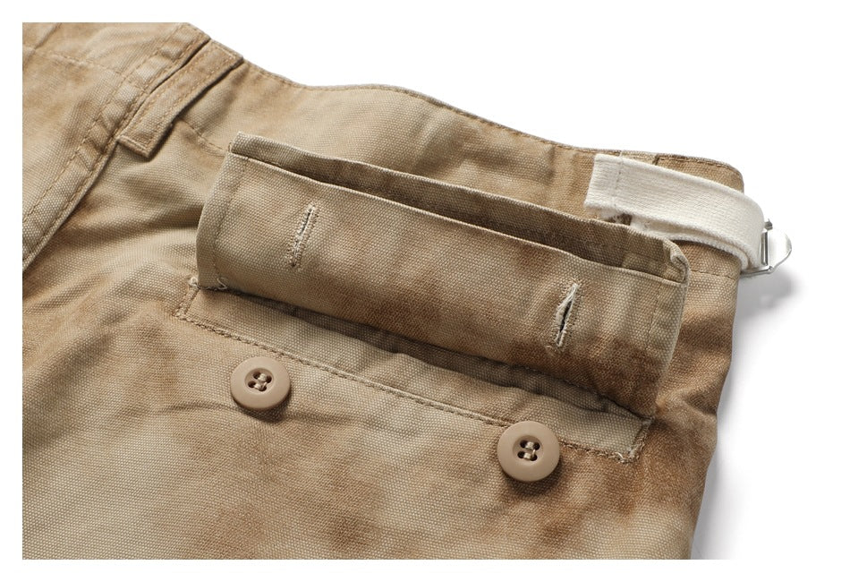 Close-up of tan cargo shorts waistband with two buttons, belt loops, and a white adjustable strap.