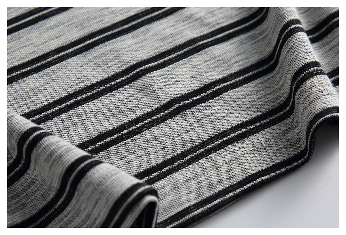 Close-up of gray knit fabric with narrow black stripes, softly draped in folds.
