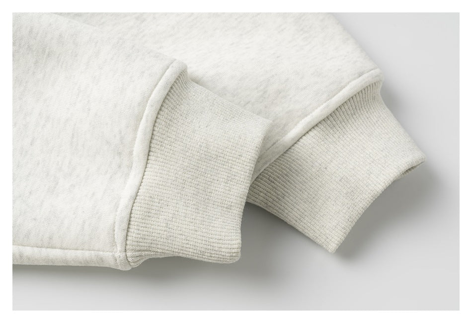 Close-up of an off-white sweatshirt sleeve with a wide ribbed cuff.