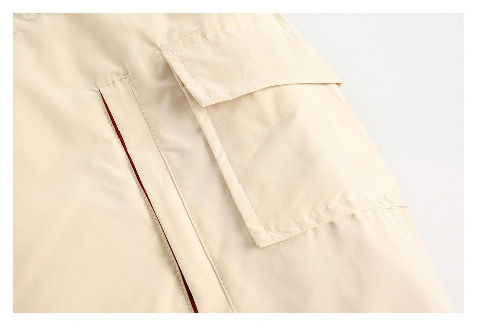 Cream garment detail with a flap pocket and a narrow vertical pocket opening.