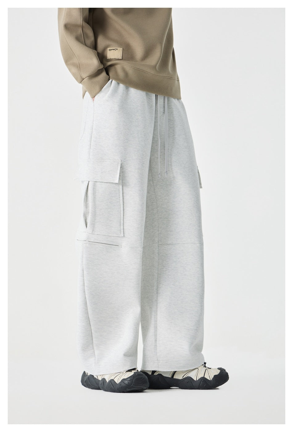 Angled side view of a model wearing light gray wide-leg cargo pants with a flap pocket.