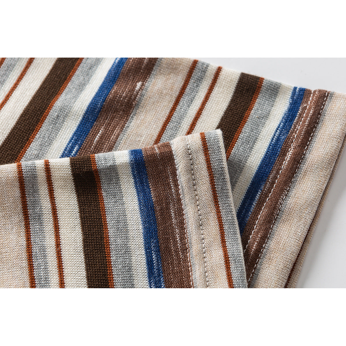 Close-up of the striped shirt fabric and folded, stitched edge in cream, brown, gray, and blue.
