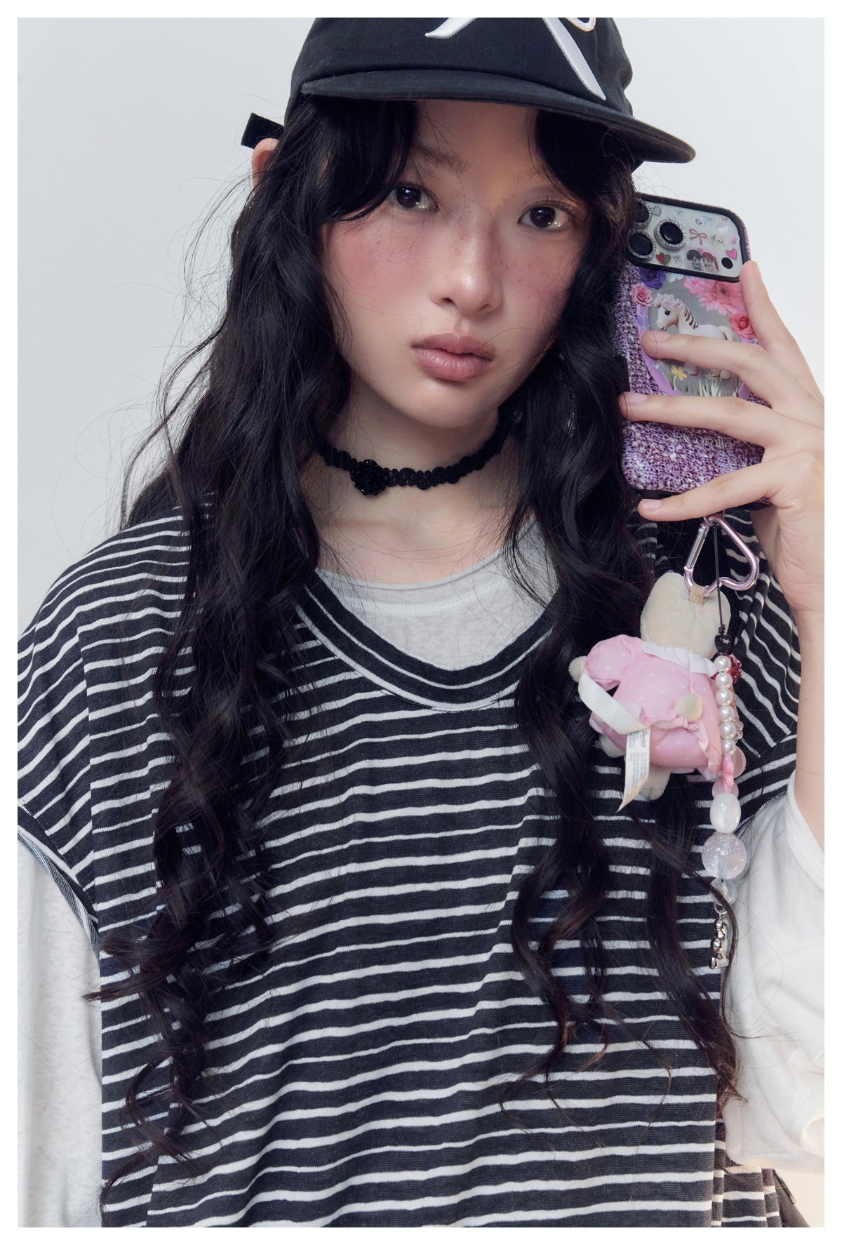 Close-up of a model wearing a black-and-white striped top layered over a light gray neckline and white sleeves.