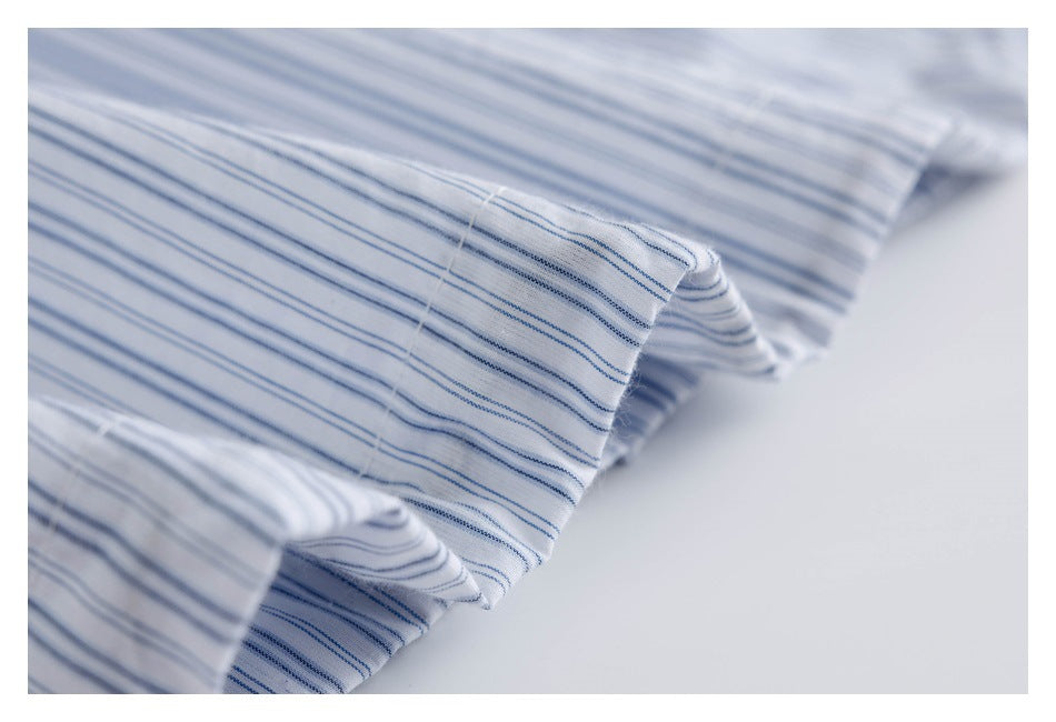 Close-up of a stitched edge on white fabric with thin blue stripes.