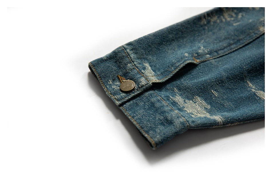 Close-up of a blue distressed denim jacket cuff with a metal button and contrast stitching.