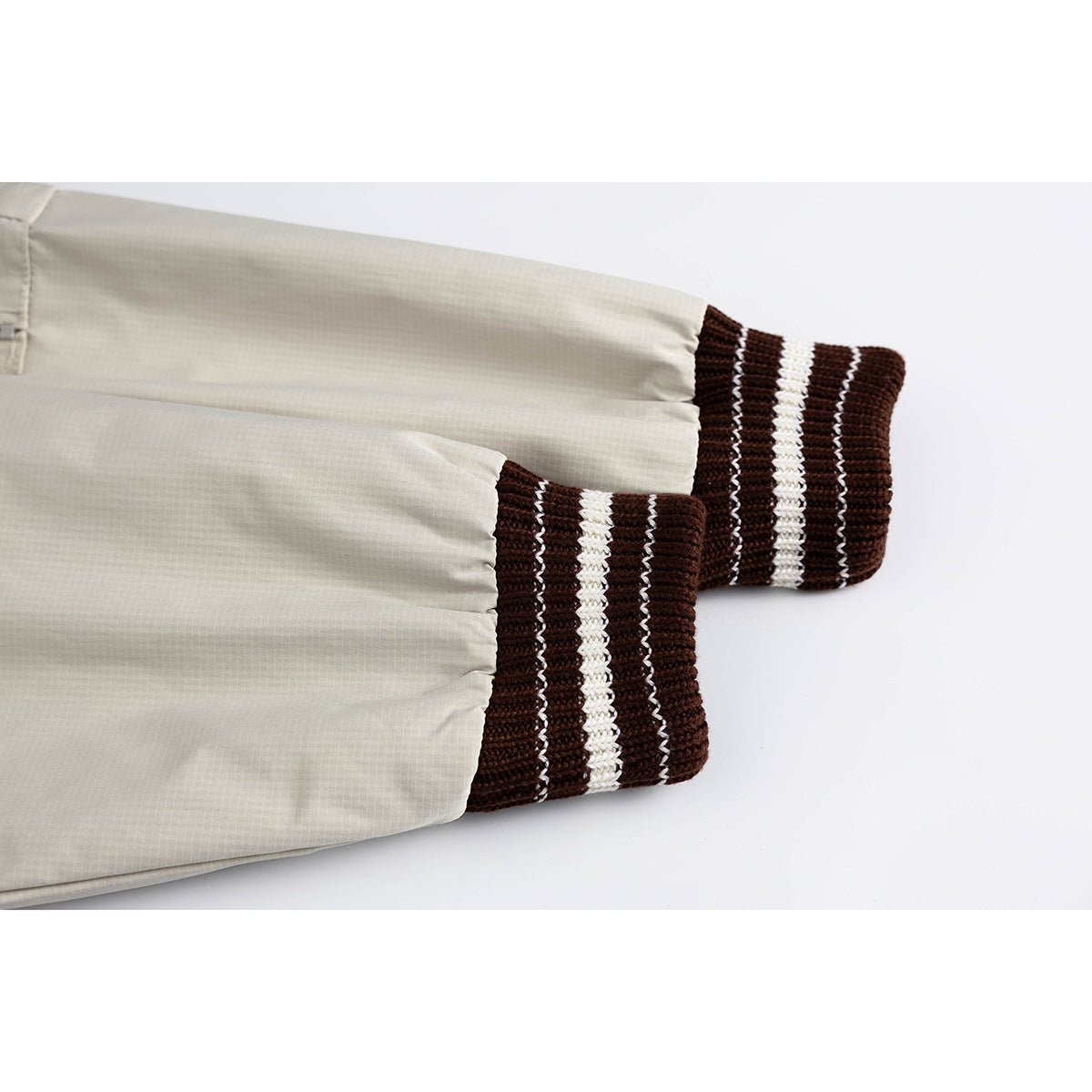Close-up of the jacket's light beige sleeves and dark brown cuffs with cream stripes.