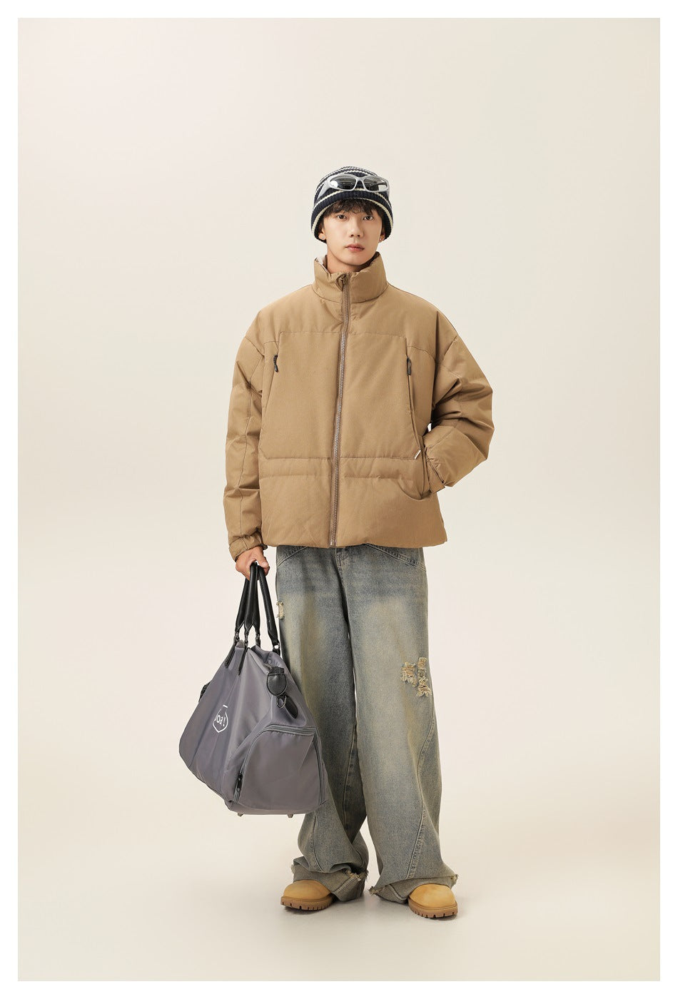 Full-length view of a model wearing a tan puffer jacket zipped to its high collar, with roomy pockets.