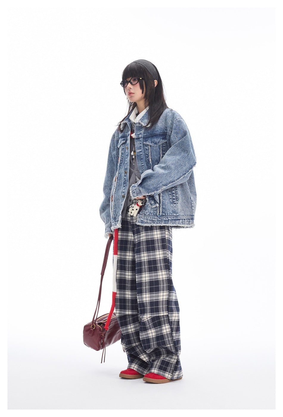 Model wearing an oversized distressed blue denim jacket, navy plaid wide-leg pants, and red shoes.