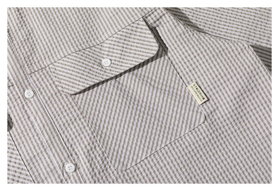 Close-up of the striped shirt's buttoned chest pocket and a small sewn label.