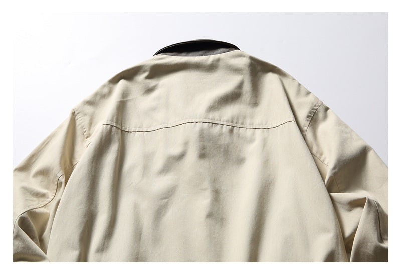 Upper back of a beige jacket laid flat, showing a curved shoulder yoke and dark collar.