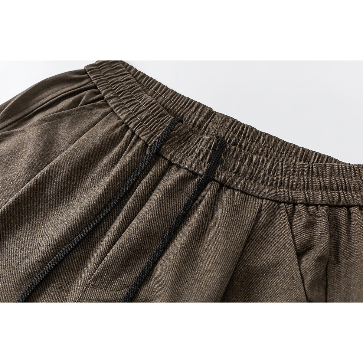 Close-up of brown wide-leg pants showing the gathered elastic waistband and black drawstring.