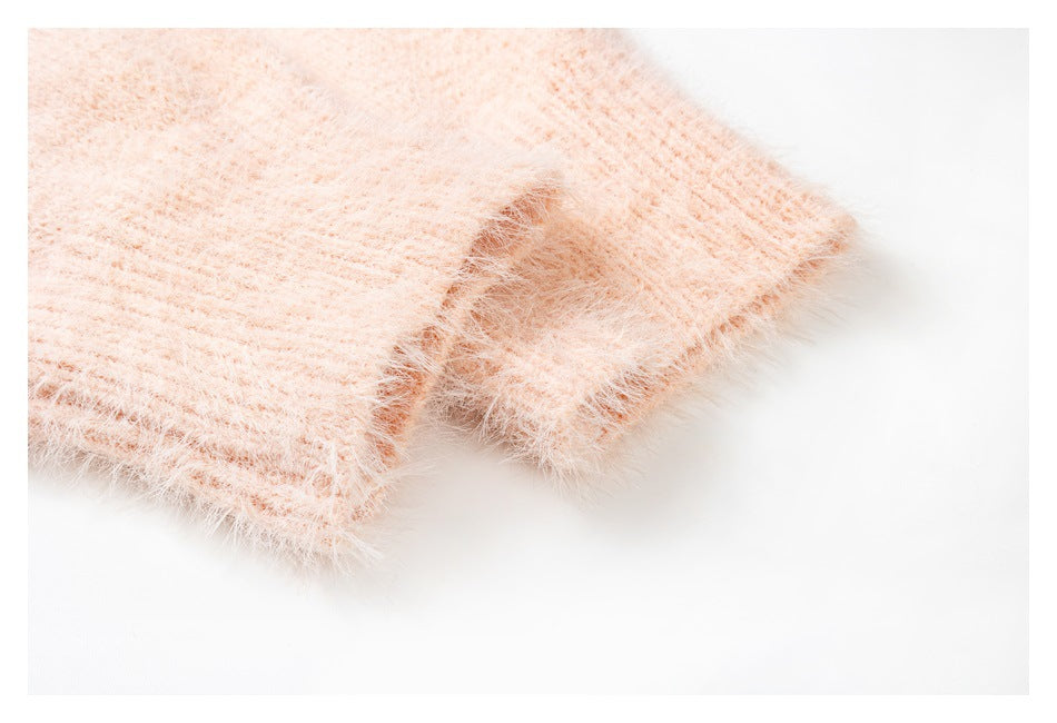 Close-up of a pale peach fuzzy knit garment showing its ribbed edge and soft surface.
