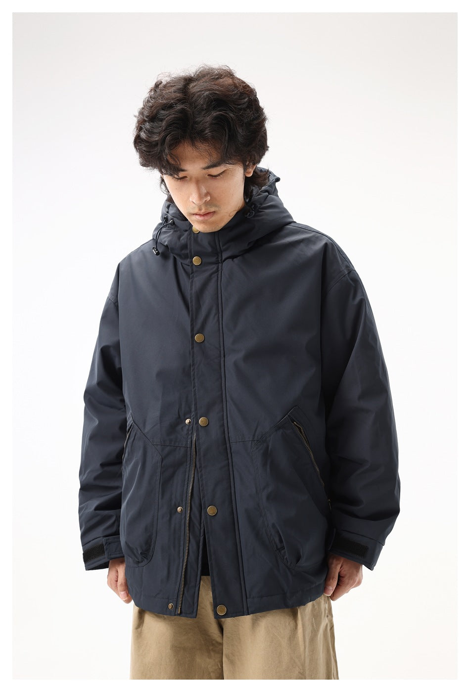 Front view of a model wearing a dark navy hooded jacket with snap and zip closures and large pockets.