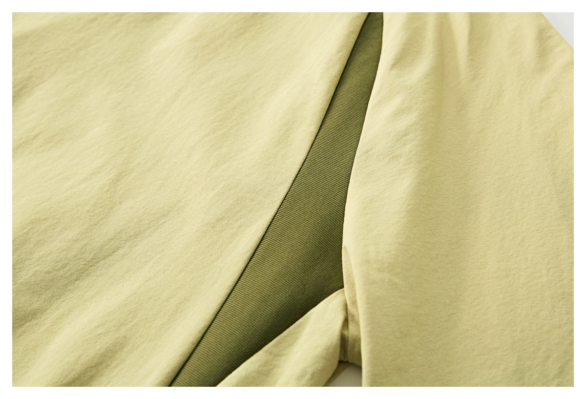 Close-up of a pale yellow T-shirt showing an olive ribbed inset between fabric panels.