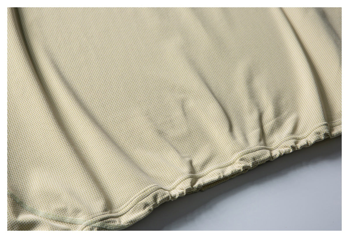 Close-up of cream fabric with tiny yellow dots and a gathered, stitched edge.
