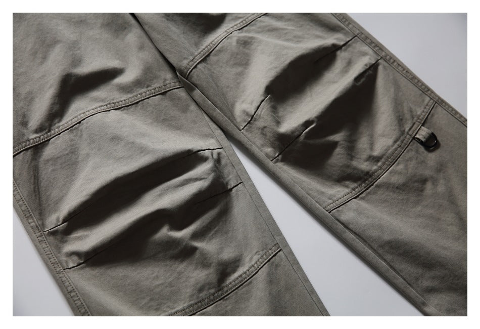 Close-up of gray-olive cargo pants showing large stitched flap pockets and a black snap.