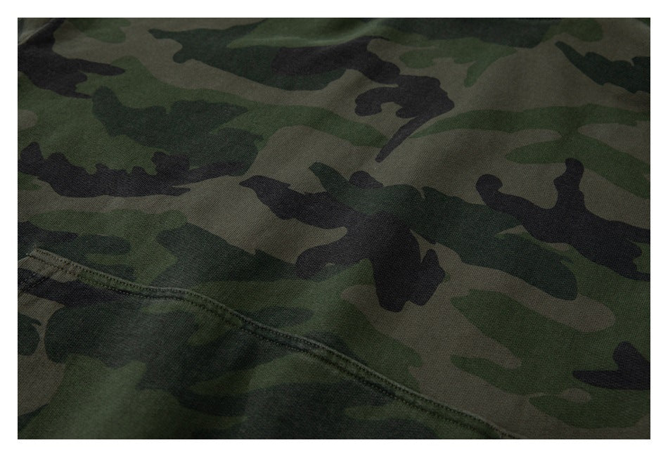 Close-up of green, brown, and black camouflage fabric with a diagonal stitched seam.