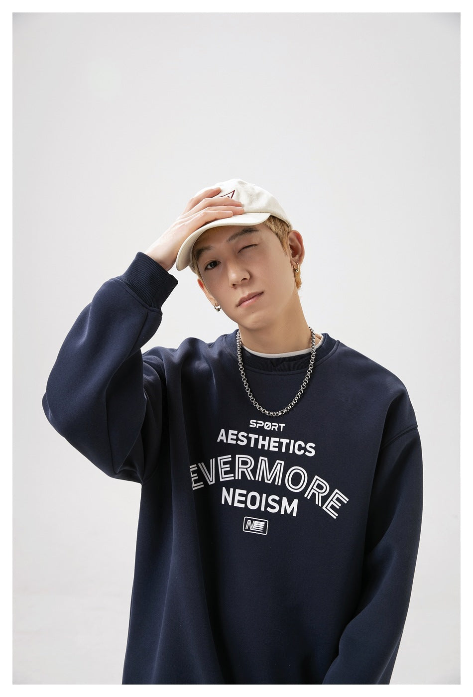Close-up of a model wearing a navy sweatshirt with large white chest lettering and a ribbed crew neck.