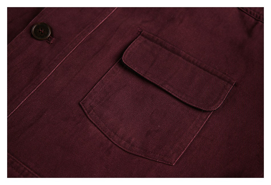 Close-up of a burgundy jacket's button and flap pocket with visible stitching.