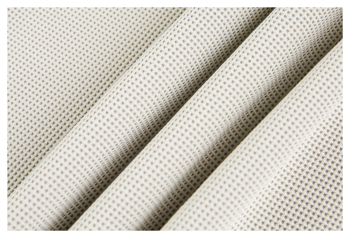 Close-up of ivory waffle-knit fabric draped into folds, showing its raised grid texture.