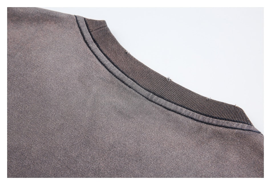 Close-up of a charcoal-brown crew neckline with ribbed trim and visible seam stitching.