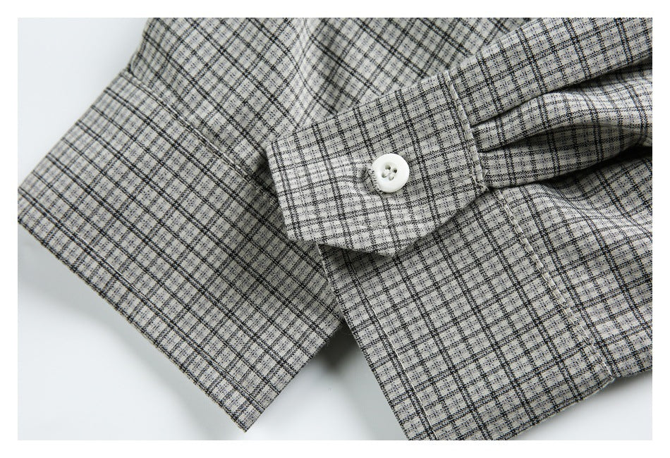 Close-up of a gray plaid garment cuff with a white button and matching fabric.