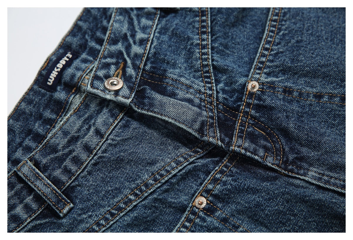 Close-up of blue jeans showing the waist closure, belt loops, rivets, and a sewn-in label.