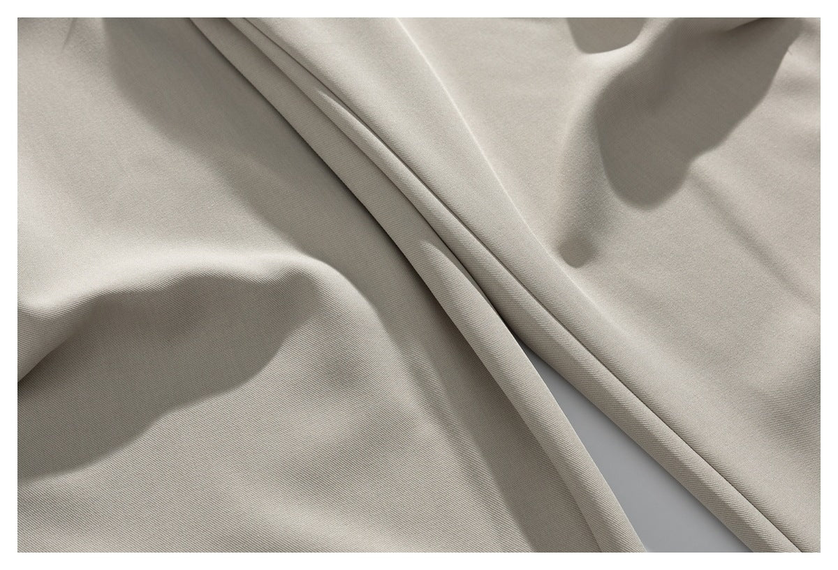 Close-up of smooth beige trouser fabric arranged in soft folds.