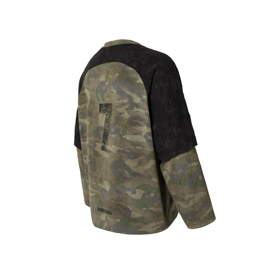 Rear three-quarter view of a long-sleeve shirt with olive camouflage panels, black raglan shoulders, and a distressed back