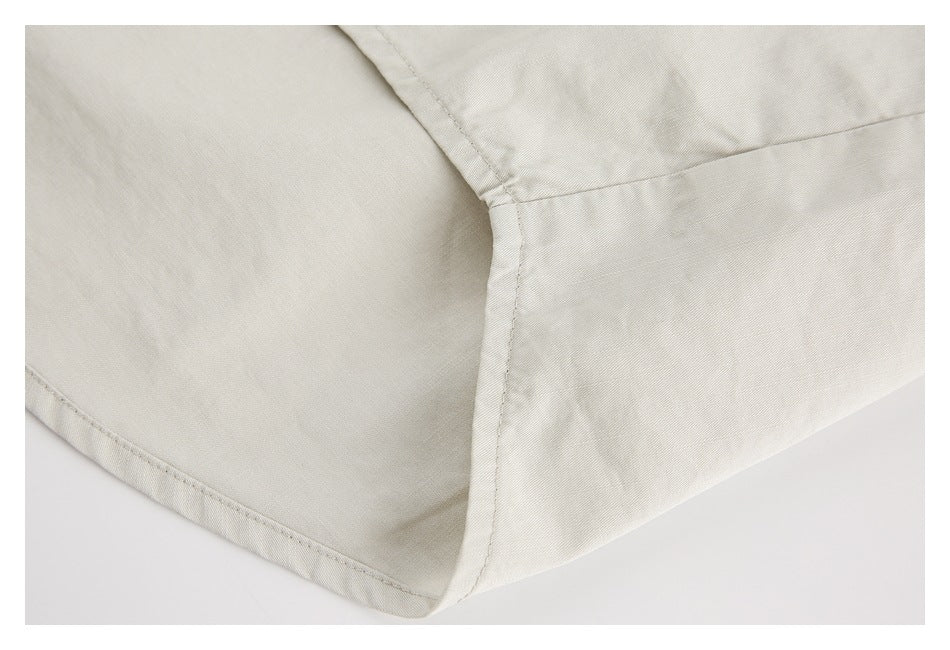 Close-up of a curved stitched seam and panel on an off-white garment.