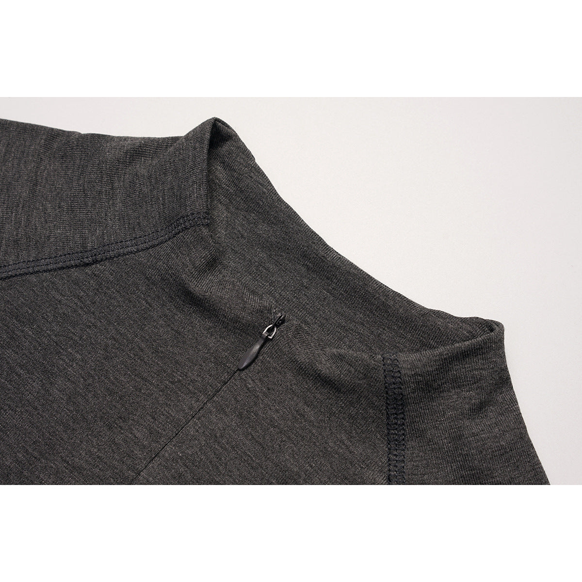 Close-up of charcoal gray knit top showing a raised neckline, seam stitching, and a small zipper.