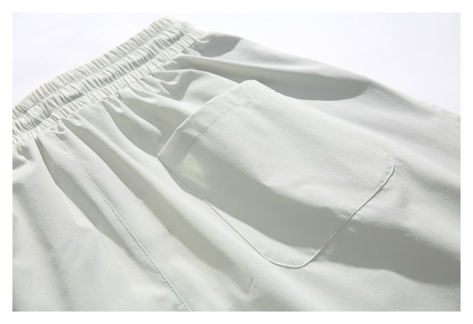 Close-up of pale gray pants showing the elastic waistband and a large stitched side pocket.