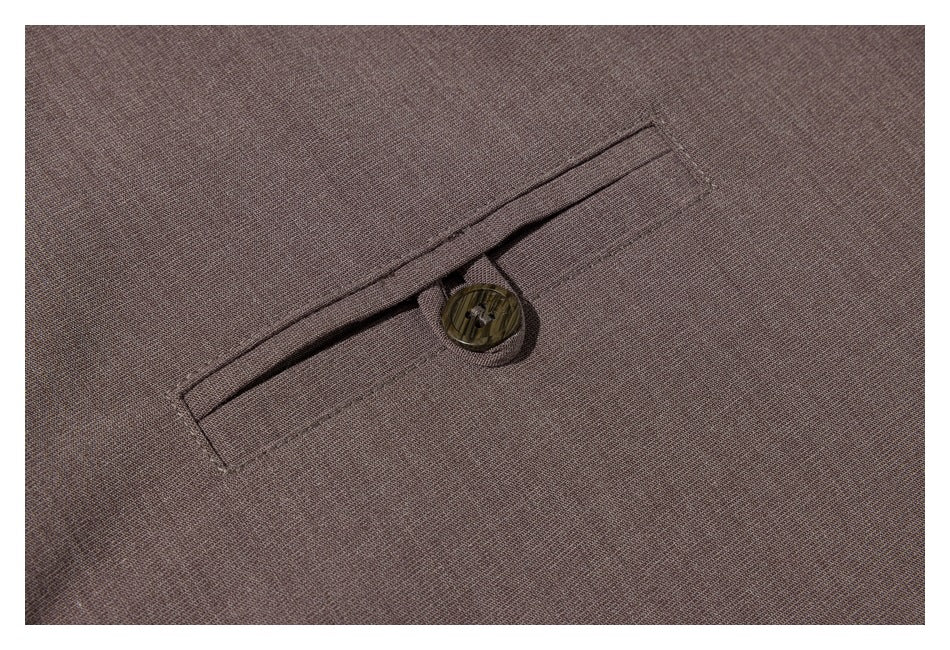 Close-up of a buttoned welt pocket on taupe shirt fabric.