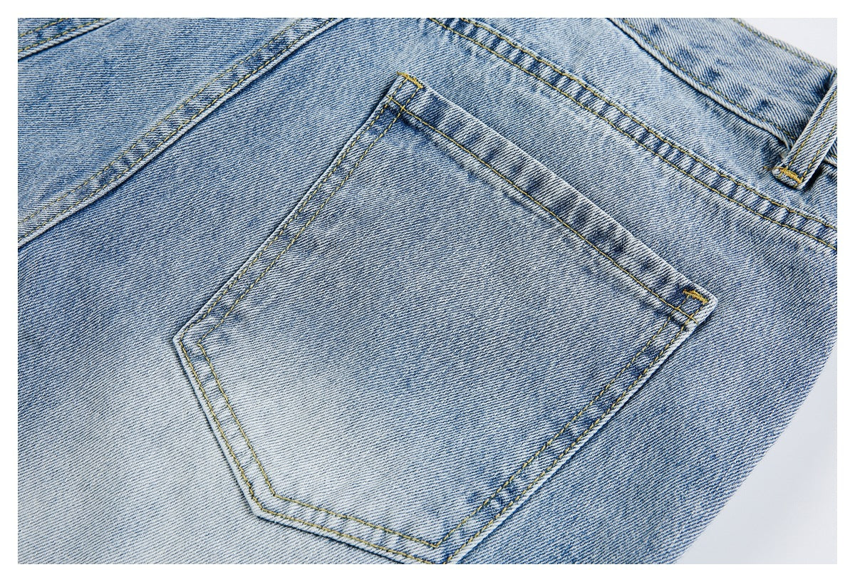 Close-up of one back patch pocket on light blue jeans with yellow stitching and faded denim.