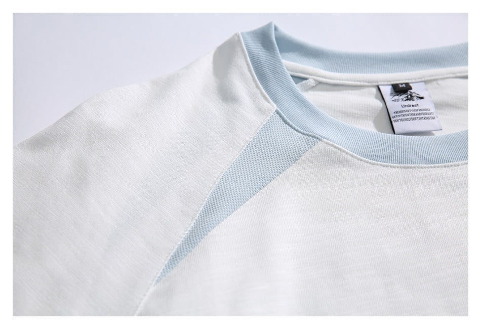 Close-up of the white T-shirt's pale blue crew neck and mesh shoulder insert.