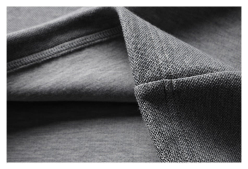 Close-up of intersecting seams on a gray garment, showing the stitching and fabric texture.