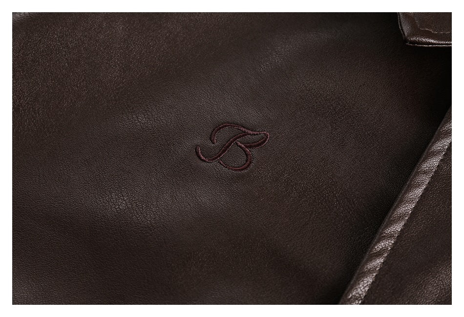 Close-up of a small embroidered emblem on the dark brown garment, beside a stitched seam.