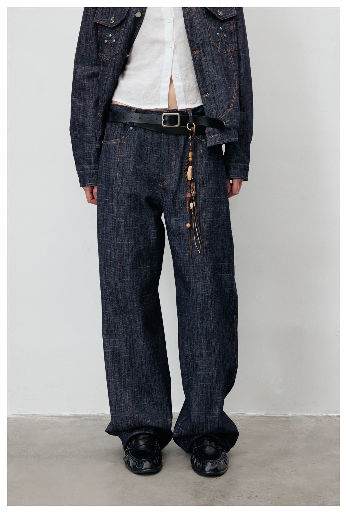Front view of a model in a dark indigo denim jacket with turquoise accents and matching wide-leg jeans.