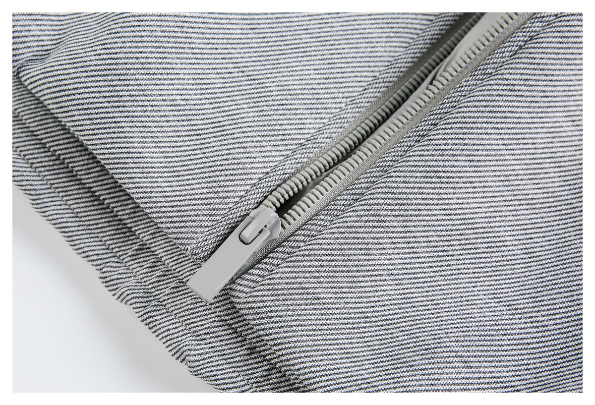 Close-up of a light gray zipper and seam on gray-and-white striped jacket fabric.