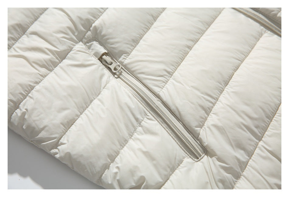 Close-up of an ivory jacket's zip pocket, stitching, and padded horizontal baffles.