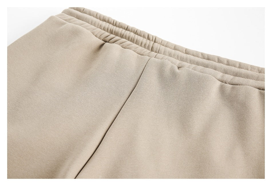 Close-up of beige pants showing the elastic waistband and front seam.