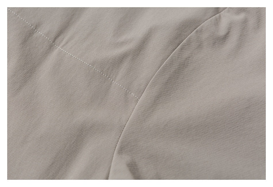 Close-up of taupe garment fabric with a curved seam and fine stitching.