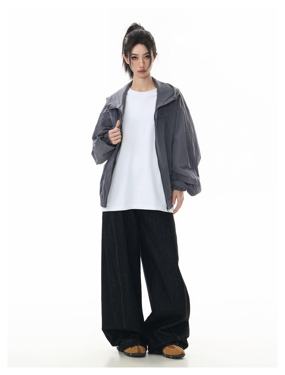 Model wearing open gray hooded jacket over white tee with wide-leg dark jeans, full-length view