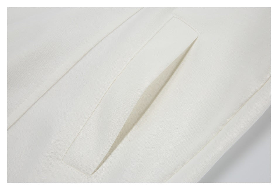 Close-up of a narrow slit pocket opening on white garment fabric.