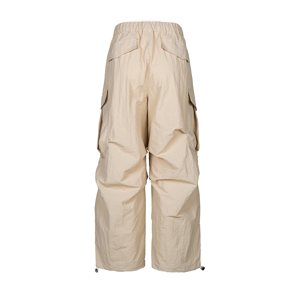 Back view of beige oversized cargo pants with an elastic waistband, flap pockets, and wide legs.