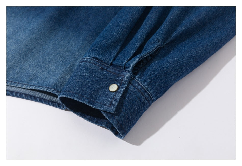 Close-up of a blue denim sleeve cuff with a pale button and gathered seam.