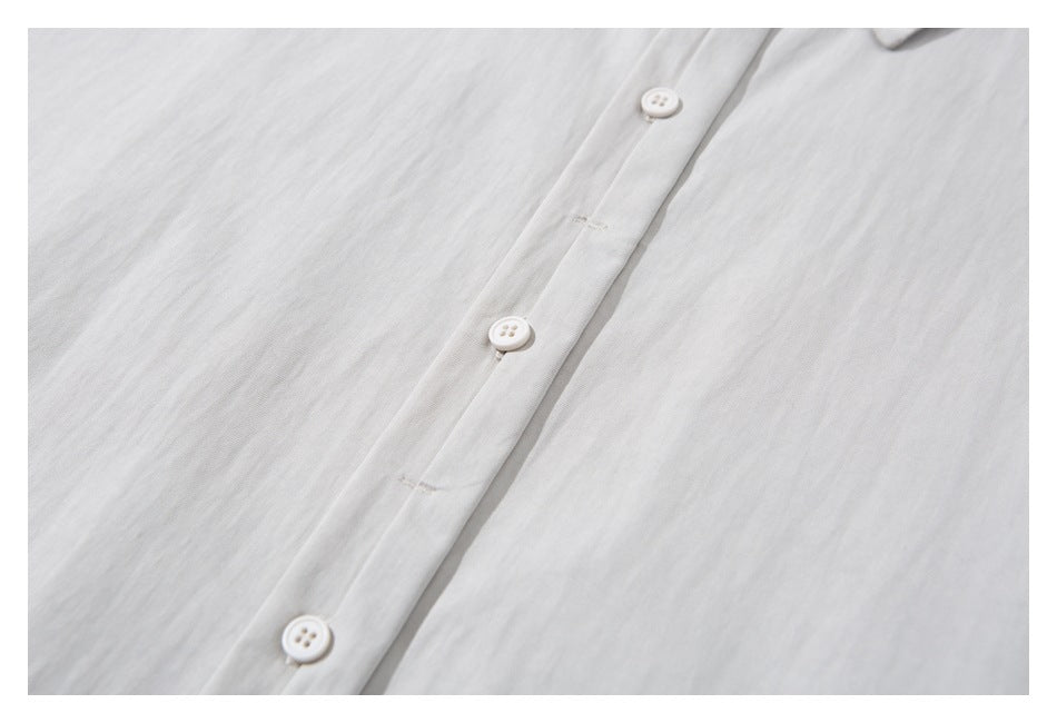 Close-up of a white shirt's button placket with three white buttons and visible fabric texture.